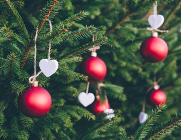 Close up van rode kerstballen en witte hartjes in dennenboom