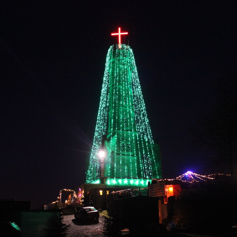 Wilhelminatoren gehuld in  groene lampjes met een piek van een rood kruis