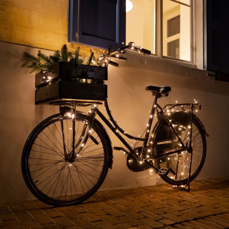 Fiets met kerstverlichting staat tegen gevel